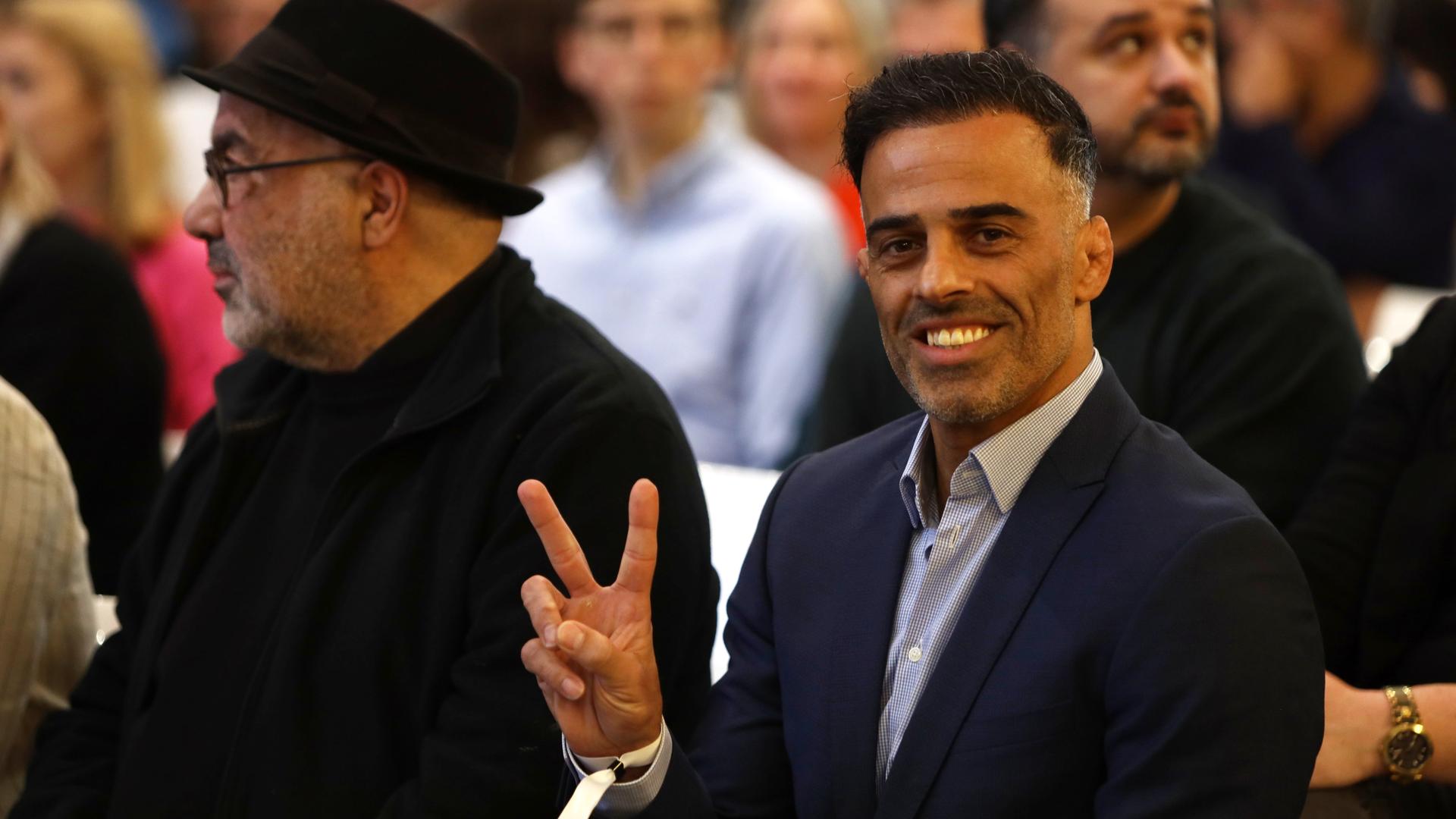 Vahid Sarlak sitzt im Publikum im deutschen Fußballmuseum bei einer Veranstaltung "Frau.Leben.Freiheit - Iranische Sportler berichten" und macht das Victory-Zeichen. Vahid Sarlak sitzt im Publikum im deutschen Fußballmuseum bei einer Veranstaltung "Frau.Leben.Freiheit - Iranische Sportler berichten" und macht das Victory-Zeichen.