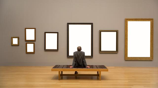 Ein Mann betrachtet leere Rahmen an einer Museumswand.