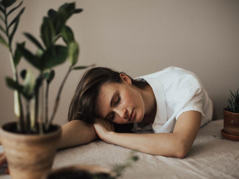 Eine Frau liegt müde am Tisch