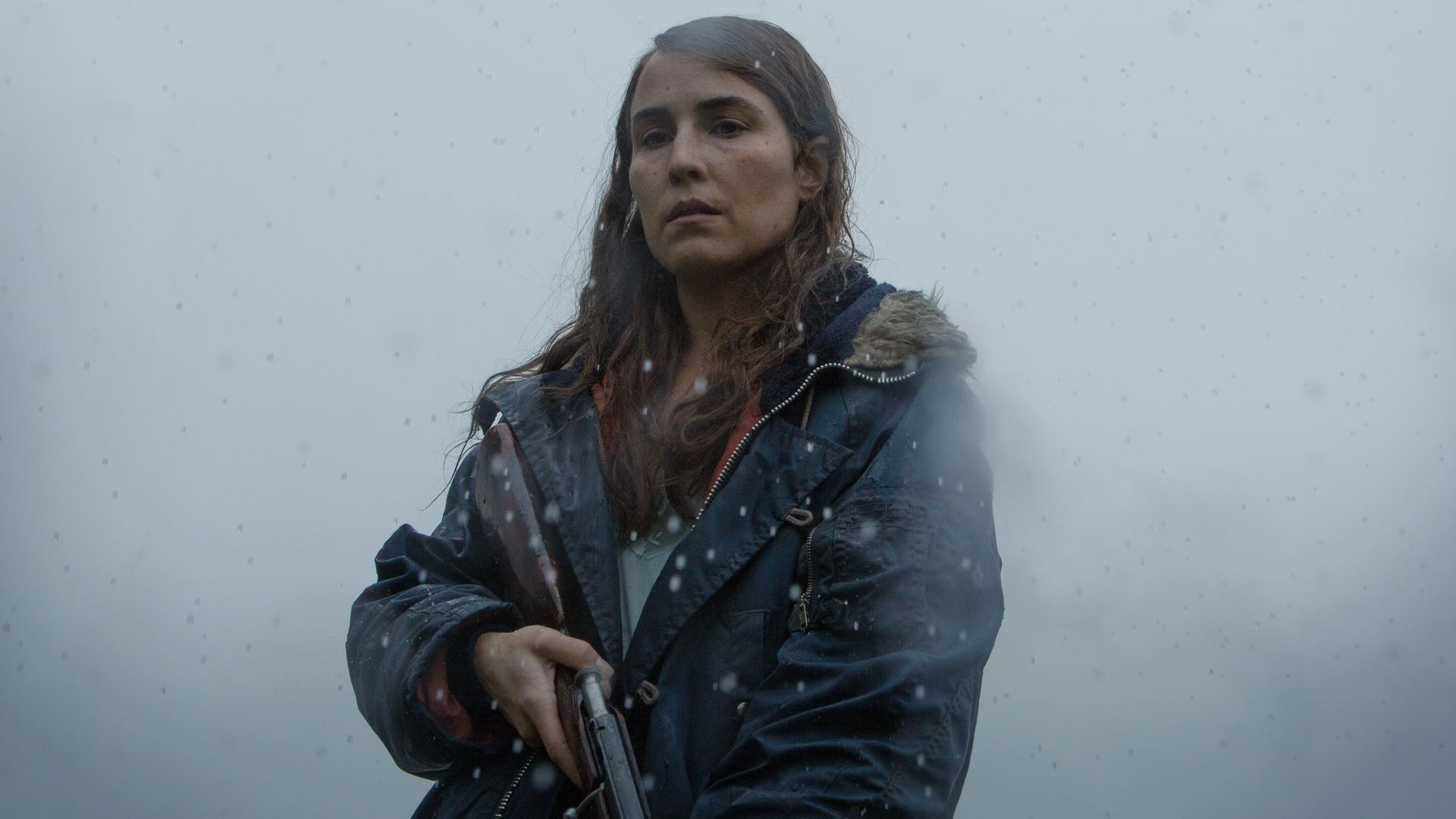 Hauptdarstellerin Noomi Rapace als Schafzüchterin Maria mit einem Gewehr in der Hand. Im Hintergrund wabert Nebel. Hauptdarstellerin Noomi Rapace als Schafzüchterin Maria mit einem Gewehr in der Hand. Im Hintergrund wabert Nebel.