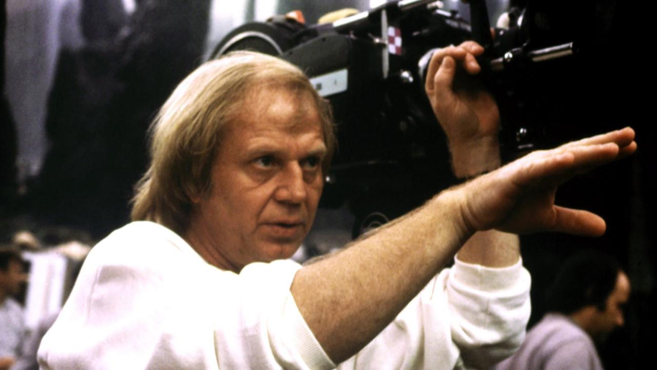 Der Regisseur Wolfgang Petersen, neben einer großen Filmkamera, gibt Handzeichen in Richtung der Schauspieler. Der Regisseur Wolfgang Petersen, neben einer großen Filmkamera, gibt Handzeichen in Richtung der Schauspieler.