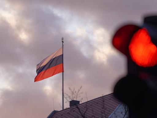 Die Flagge der Russischen Botschaft weht am frühen Morgen vor einer roten Ampel. Die russische Armee ist am frühen Morgen in die Ukraine einmarschiert.