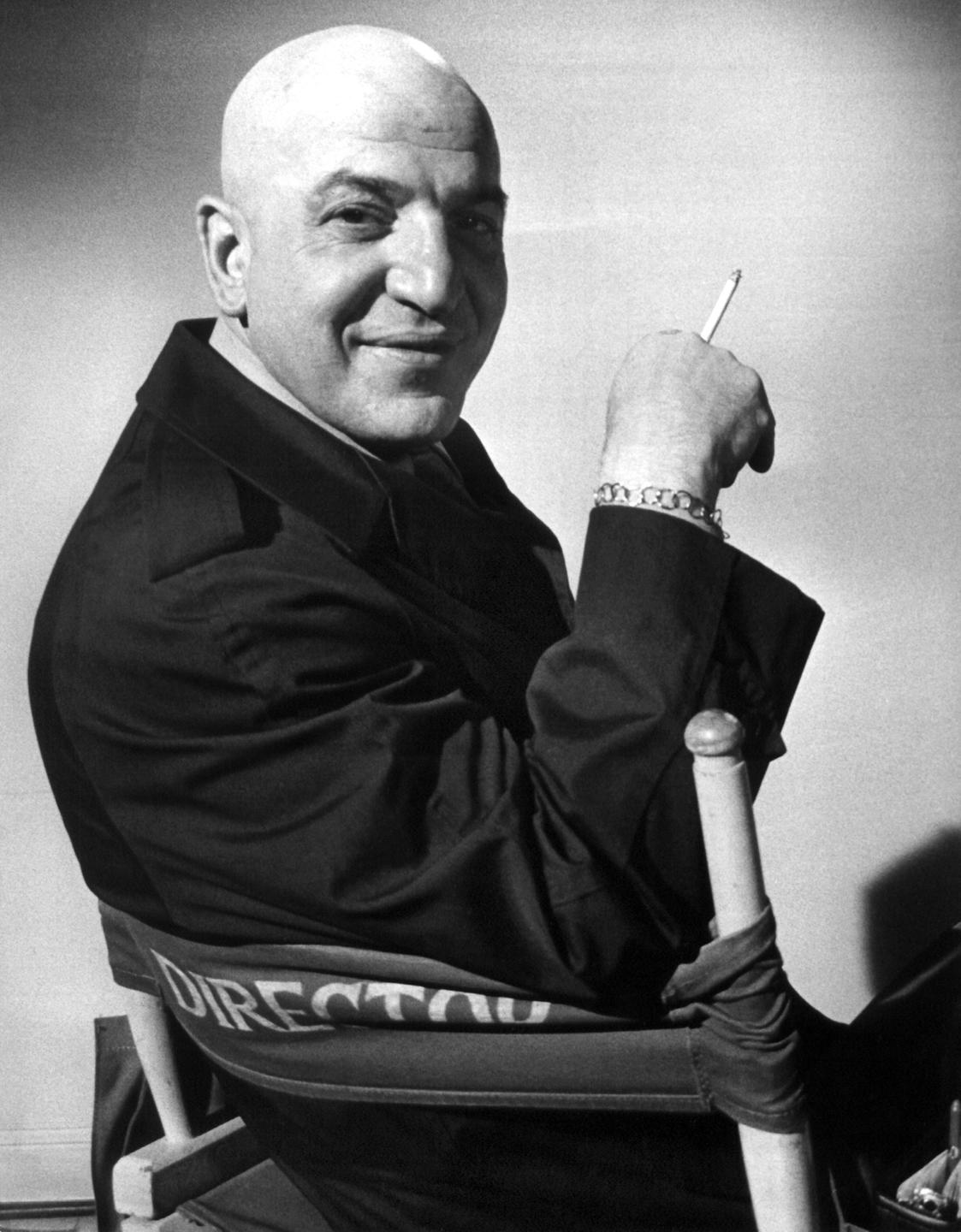 US-Schauspieler Telly Savalas am Rande von Dreharbeiten zur Kultserie "Einsatz in Manhattan". Er sitzt auf einem Stuhl und raucht. US-Schauspieler Telly Savalas am Rande von Dreharbeiten zur Kultserie "Einsatz in Manhattan". Er sitzt auf einem Stuhl und raucht.