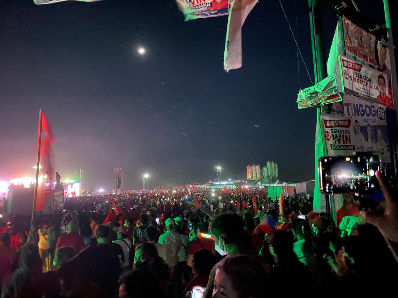 Eine riesige Menschenmenge steht zwischen roten Fahnen und Wahlkplakaten in der Nacht auf einem weitläufigen Platz von Flutlicht angestrahlt.