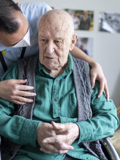Ein Altenpfleger redet mit einem Bewohner im Pflegeheim