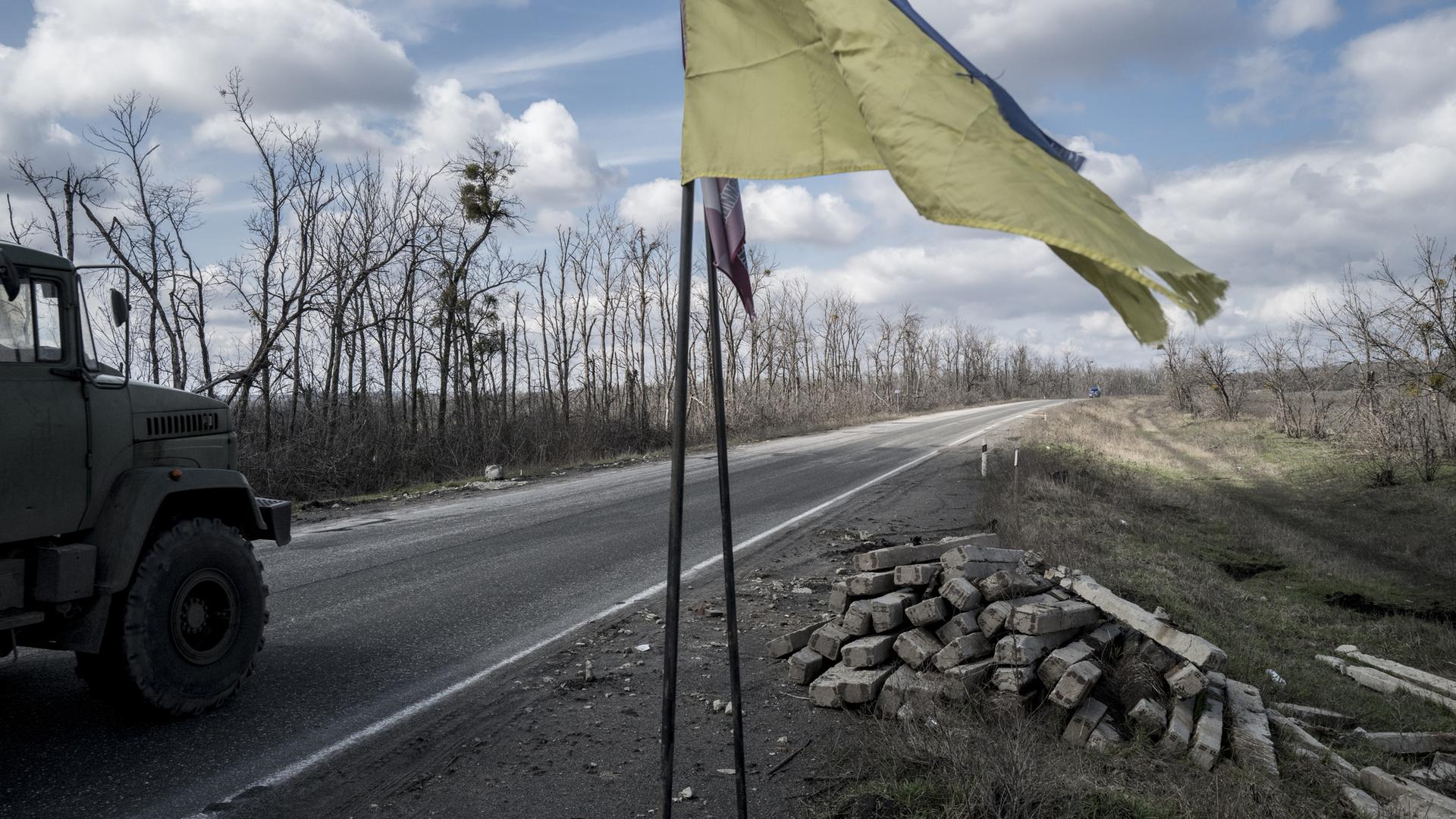 Ein Truck fährt auf einer Straße nach Slowiansk an einer ukrainischen Flagge vorbei. Ein Truck fährt auf einer Straße nach Slowiansk an einer ukrainischen Flagge vorbei.
