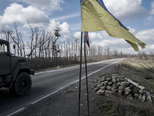 Ein Truck fährt auf einer Straße nach Slowiansk an einer ukrainischen Flagge vorbei.