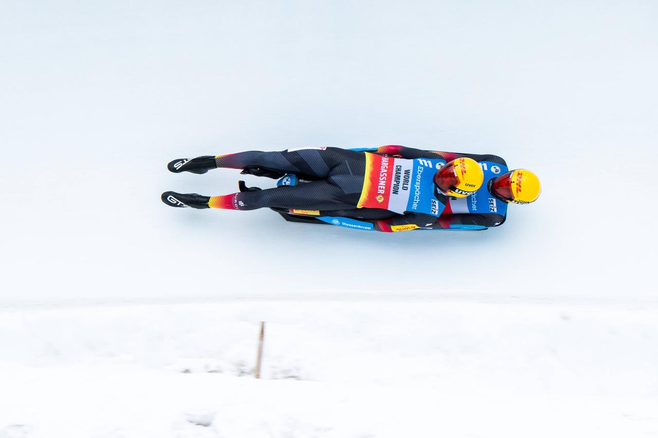 Die deutschen Toni Eggert und Sascha Benecken beim Rennen in St. Moritz. Die beiden liegen aufeinander auf ihrem Rennrodel und fahren auf der weißen vereisten Rodelbahn. Die deutschen Toni Eggert und Sascha Benecken beim Rennen in St. Moritz. Die beiden liegen aufeinander auf ihrem Rennrodel und fahren auf der weißen vereisten Rodelbahn.