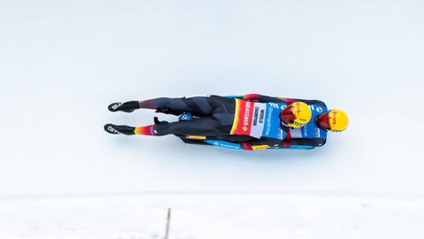 Die deutschen Toni Eggert und Sascha Benecken beim Rennen in St. Moritz. Die beiden liegen aufeinander auf ihrem Rennrodel und fahren auf der weißen vereisten Rodelbahn.