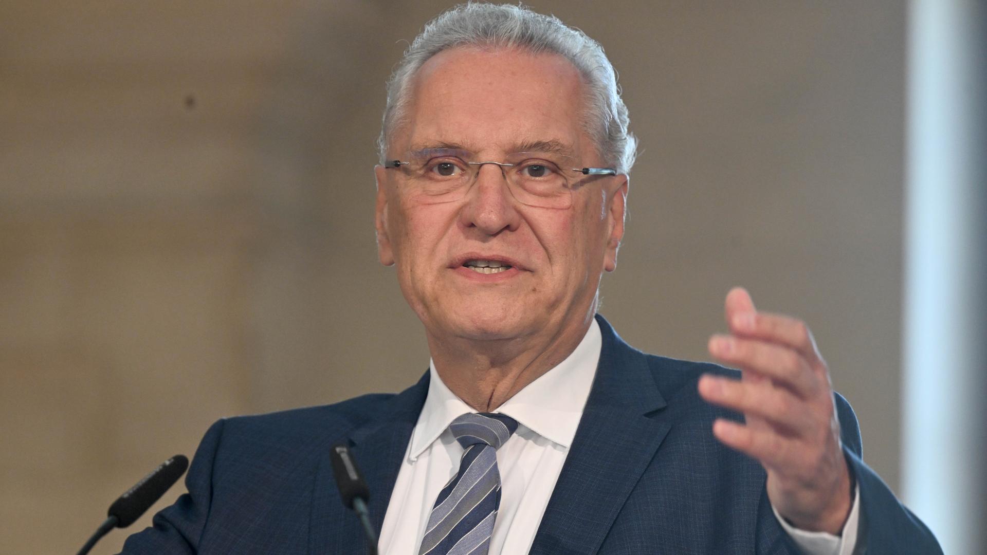 Der Bayerische Innenminister Joachim Herrmann spricht mit erhobener Hand vor zwei Mikrofonen. Der Bayerische Innenminister Joachim Herrmann spricht mit erhobener Hand vor zwei Mikrofonen.