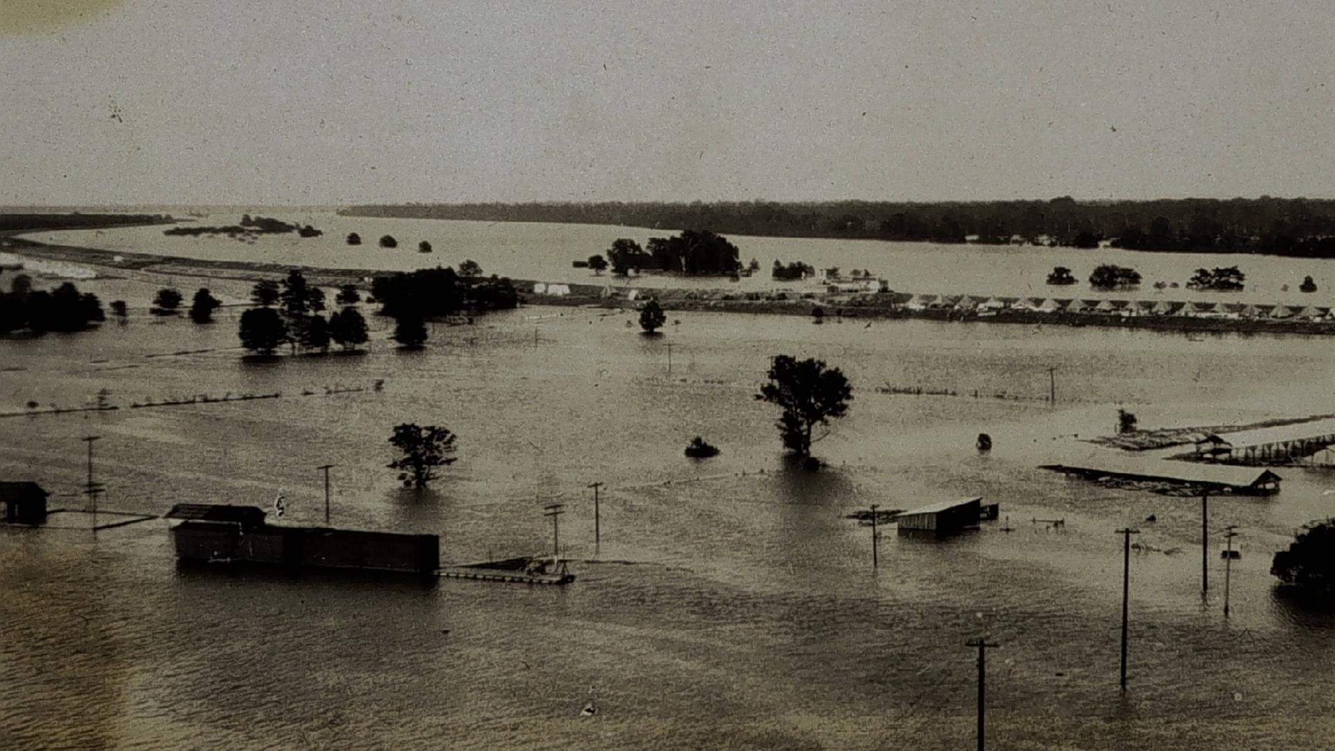 Die historische Schwarz-Weiß-Fotografie aus dem Jahr 1927 zeigt Wassermassen, aus denen vereinzelt Dächer eines Zeltcamps für Flüchtlinge herausragen. Die historische Schwarz-Weiß-Fotografie aus dem Jahr 1927 zeigt Wassermassen, aus denen vereinzelt Dächer eines Zeltcamps für Flüchtlinge herausragen.