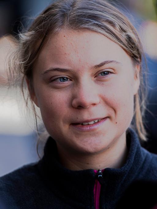 Die schwedische Klimaaktivistin Greta Thunberg schaut freundlich aber ernst eine Person an, mit der sie im Gespräch ist, und die mit dem Rücken zur Kamera steht.