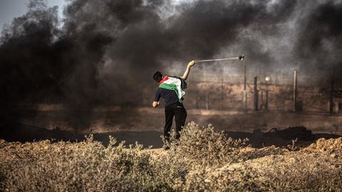 Ein Palästinenser schleudert einen Stein über die iraelische Grenze, 25.08.2021.