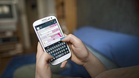 Ein 14-jähriges Mädchen führt auf ihrem Smartphone mit der App Whatsapp eine Konversation mit einem Freund (Gestelltes Foto).