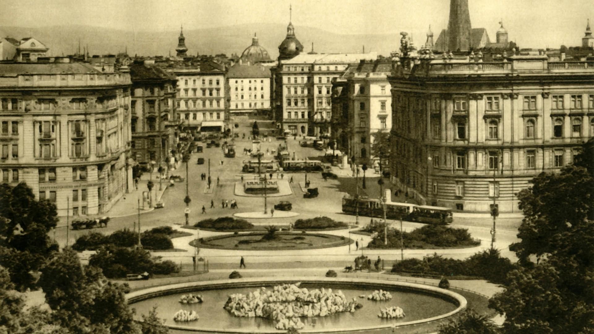 Schwarz-Weiß-Foto von Wien in den 1930er-Jahren. Zu sehen sind eine Parkanlage mit einem Springbrunnen und mehrstöckige Wohnhäuser.  