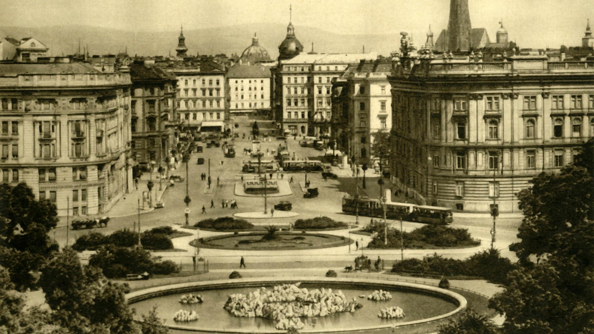Schwarz-Weiß-Foto von Wien in den 1930er-Jahren. Zu sehen sind eine Parkanlage mit einem Springbrunnen und mehrstöckige Wohnhäuser. Schwarz-Weiß-Foto von Wien in den 1930er-Jahren. Zu sehen sind eine Parkanlage mit einem Springbrunnen und mehrstöckige Wohnhäuser.