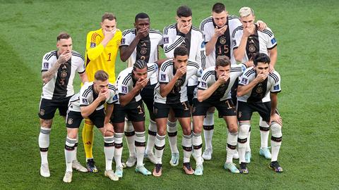 Die Spieler der deutschen Fußballnationalmannschaft stellen sich zum Foto auf und halten sich die Hand vor den Mund.
