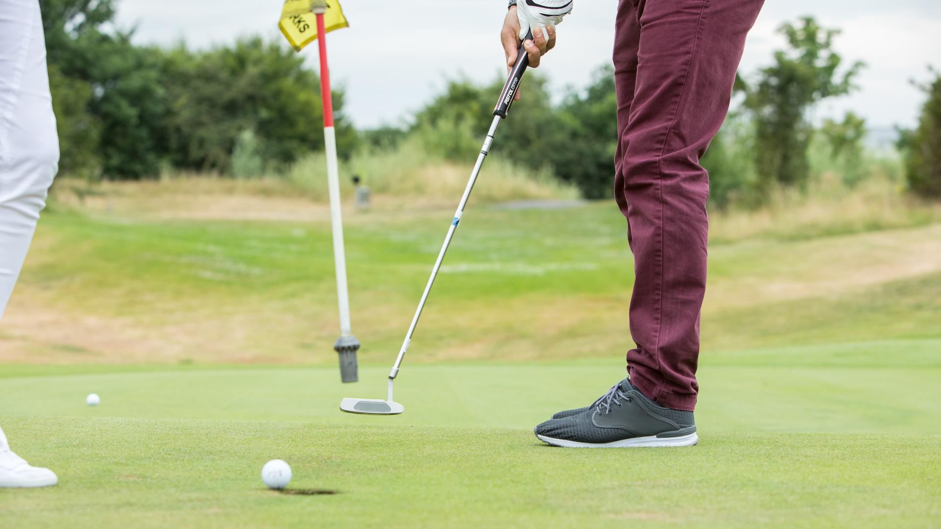 Ein Golfspieler locht auf einem Golfplatz in Köln den Golfball ein. Ein Golfspieler locht auf einem Golfplatz in Köln den Golfball ein.