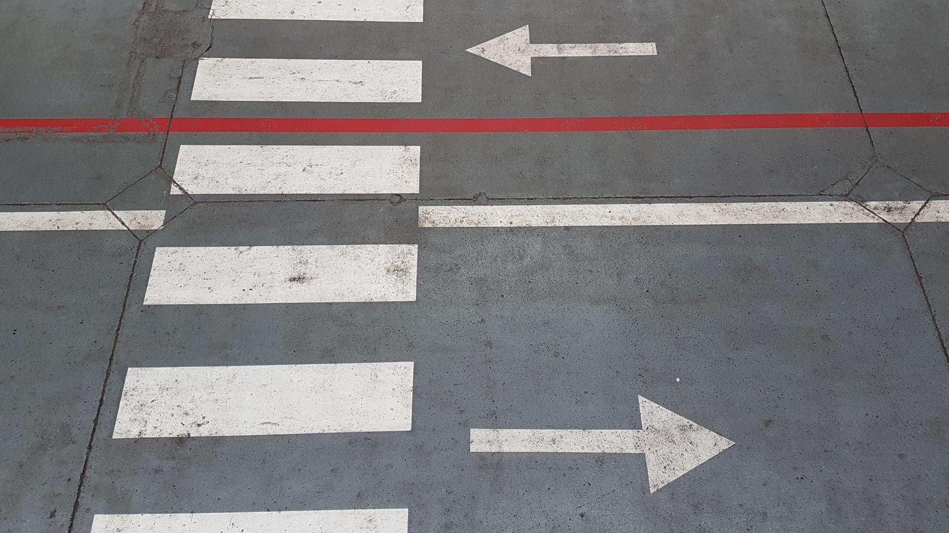 Eine Straße mit einem Zebrastreifen und zwei Pfeilen (einer nach rechts und einer nach links) Eine Straße mit einem Zebrastreifen und zwei Pfeilen (einer nach rechts und einer nach links)