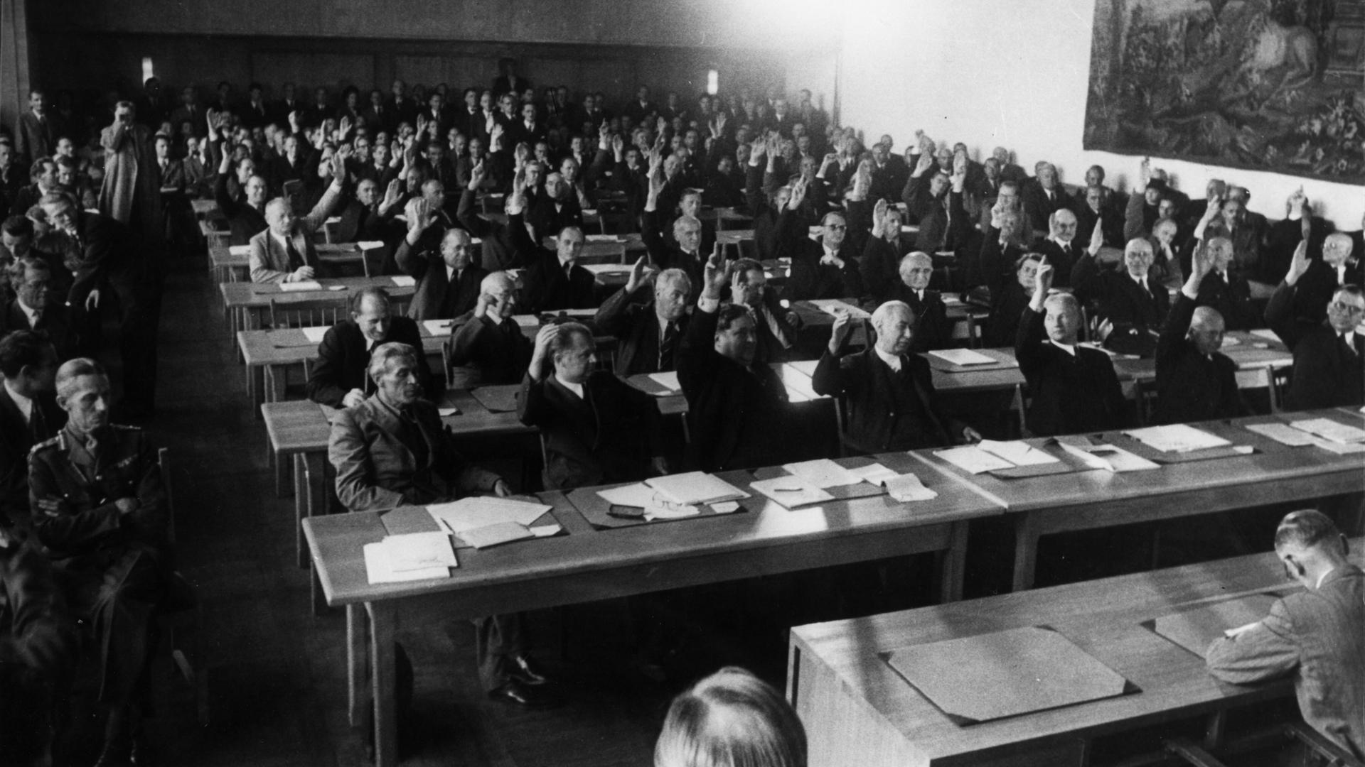 Annahme des Grundgesetzes: Das Plenum des Parlamentarischen Rates nimmt in 3. Lesung am 8. Mai 1949 den revidierten Grundgesetzentwurf mit 53 gegen 12 Stimmen an. Annahme des Grundgesetzes: Das Plenum des Parlamentarischen Rates nimmt in 3. Lesung am 8. Mai 1949 den revidierten Grundgesetzentwurf mit 53 gegen 12 Stimmen an.