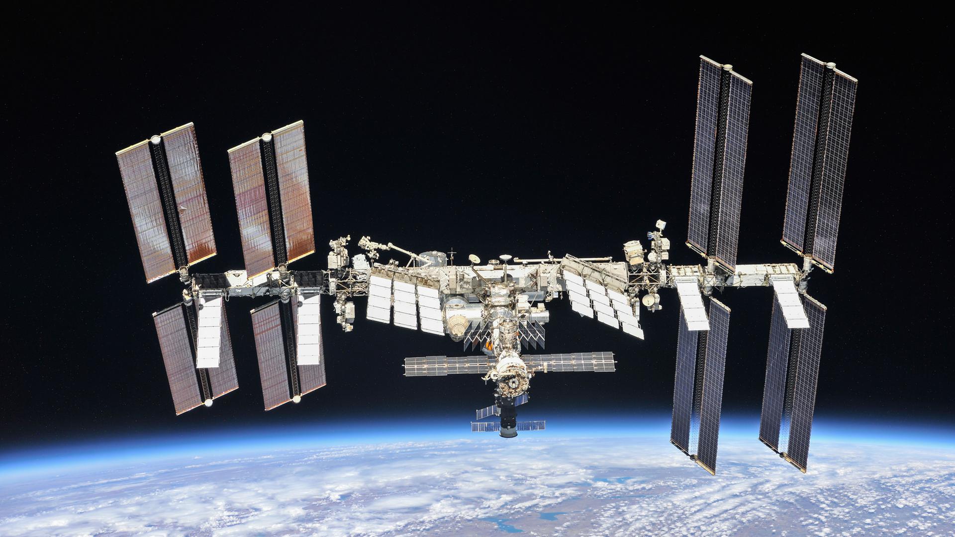 Die Internationale Raumstation in der Schwärzes des Alls, am unteren Bildrand der blaue Planet Erde Die Internationale Raumstation in der Schwärzes des Alls, am unteren Bildrand der blaue Planet Erde