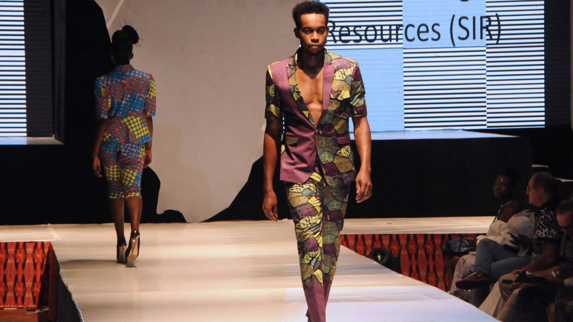 Die Lagos Fashion Week im Jahr 2016. Zu sehen: Ein modisch gekleideter junger Mann geht über den Laufsteg. 