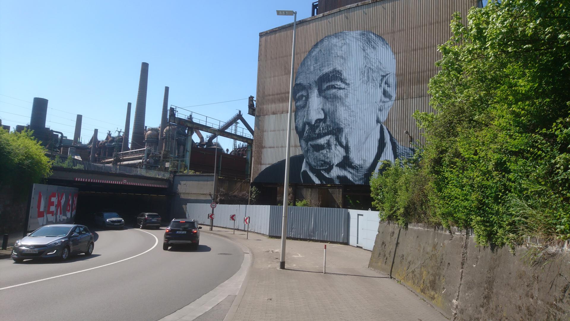 Monumentale Kunst von Hendrik Beikirch: Das gespraytes Bild zeigt den türkische Arbeiter Kaya Urhan an einer Fassade Monumentale Kunst von Hendrik Beikirch: Das gespraytes Bild zeigt den türkische Arbeiter Kaya Urhan an einer Fassade