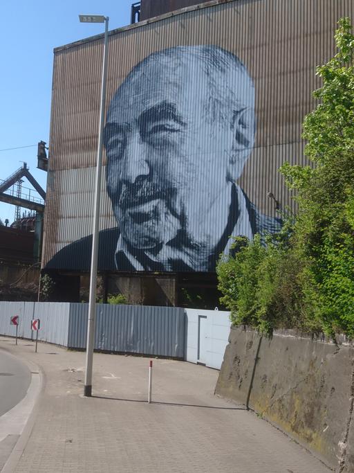  Monumentale Kunst von Hendrik Beikirch: Das gespraytes Bild zeigt den türkische Arbeiter Kaya Urhan an einer Fassade