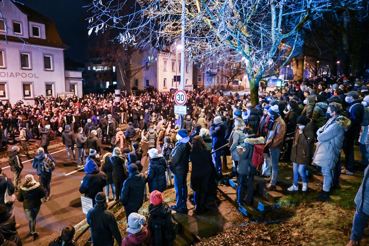 Passanten schauen den Teilnehmern eines sogenannten Spazierganges gegen die Corona-Maßnahmen durch die Innenstadt von Ravensburg zu. Passanten schauen den Teilnehmern eines sogenannten Spazierganges gegen die Corona-Maßnahmen durch die Innenstadt von Ravensburg zu.
