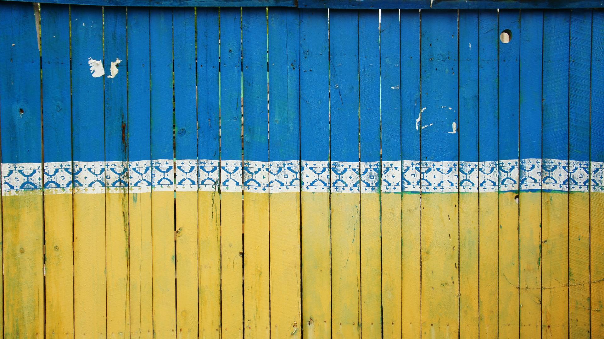 Zaunlatten sind so in blau und gelb gestrichen, dass sie die Flagge der Ukraine abbilden.