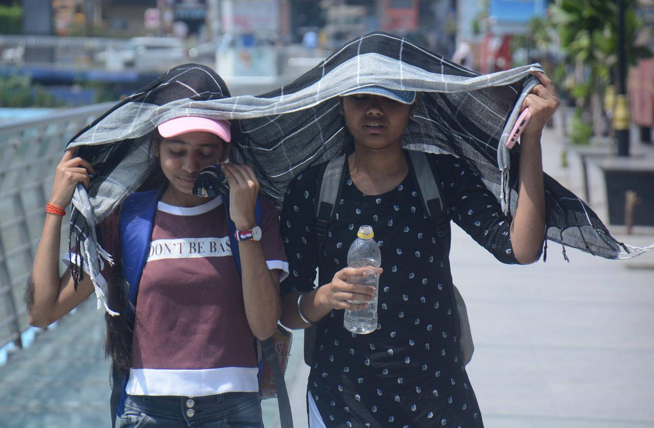 Zwei junge Mädchen auf der Straße suchen Schutz unter eine großen Tuch, die Wasserflaschen in der Hand.