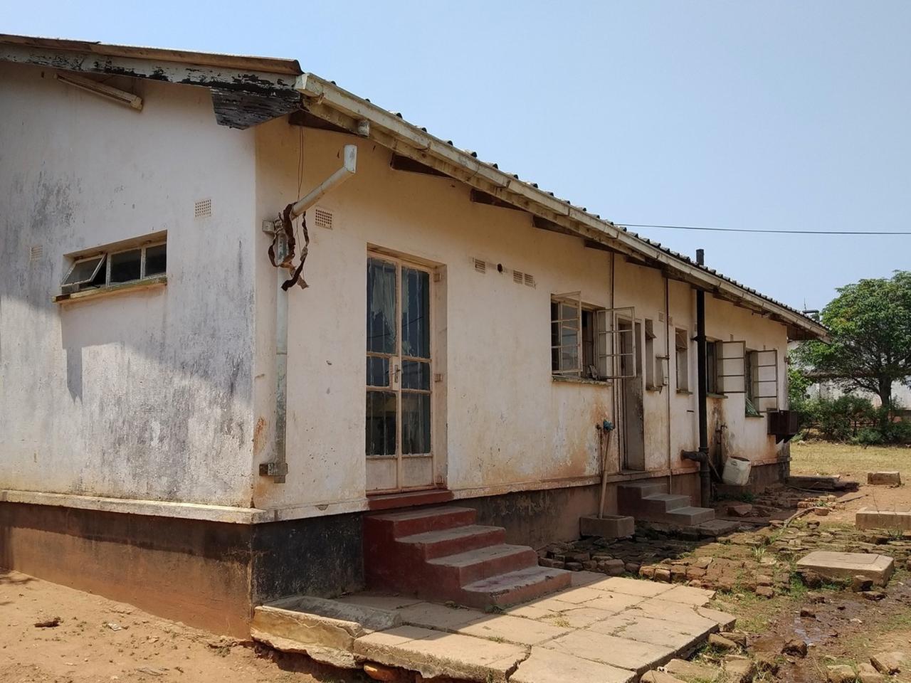 Die Wände des Hauses sind verdreckt, es sieht von außen heruntergekommen aus. Um das Haus sind Sand und Bäume. Die Wände des Hauses sind verdreckt, es sieht von außen heruntergekommen aus. Um das Haus sind Sand und Bäume.