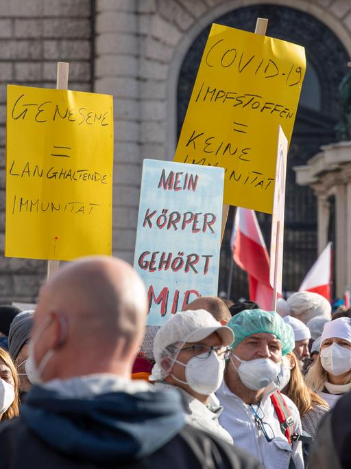 Demonstranten gegen die Coronamaßnahmen halten am 20.11.2021 in Wien Plakate gegen die in Österreich geplante Impfpflicht in die Höhe