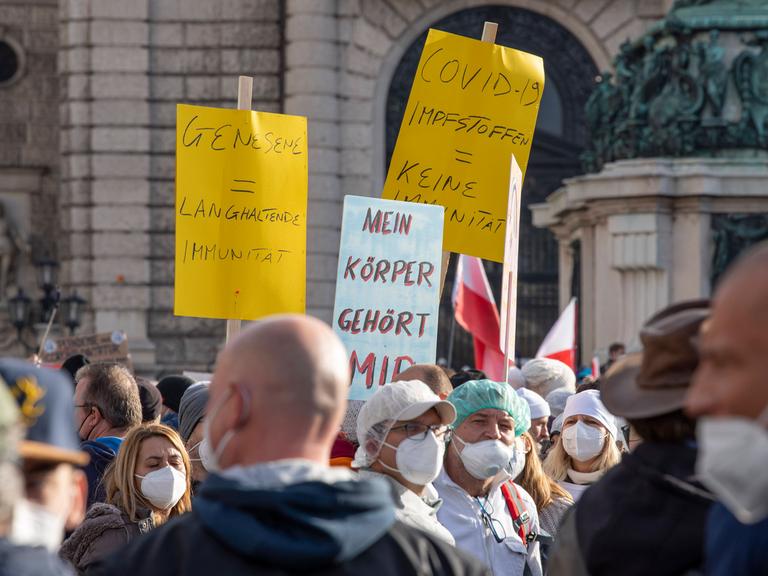 Demonstranten gegen die Coronamaßnahmen halten am 20.11.2021 in Wien Plakate gegen die in Österreich geplante Impfpflicht in die Höhe