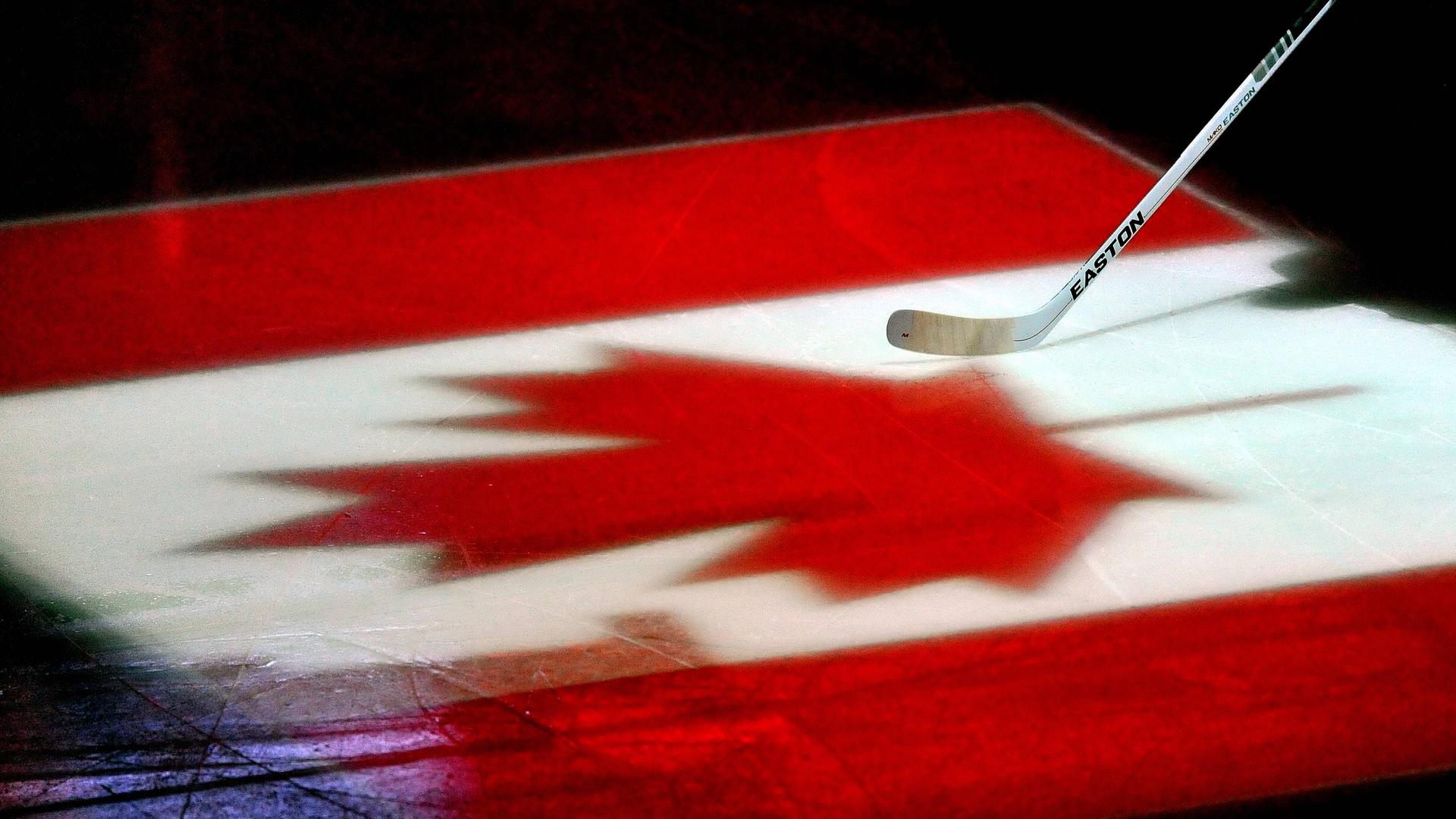 Ein Eishockeyschläger auf einer auf das Eis projizierte kanadische Flagge. 