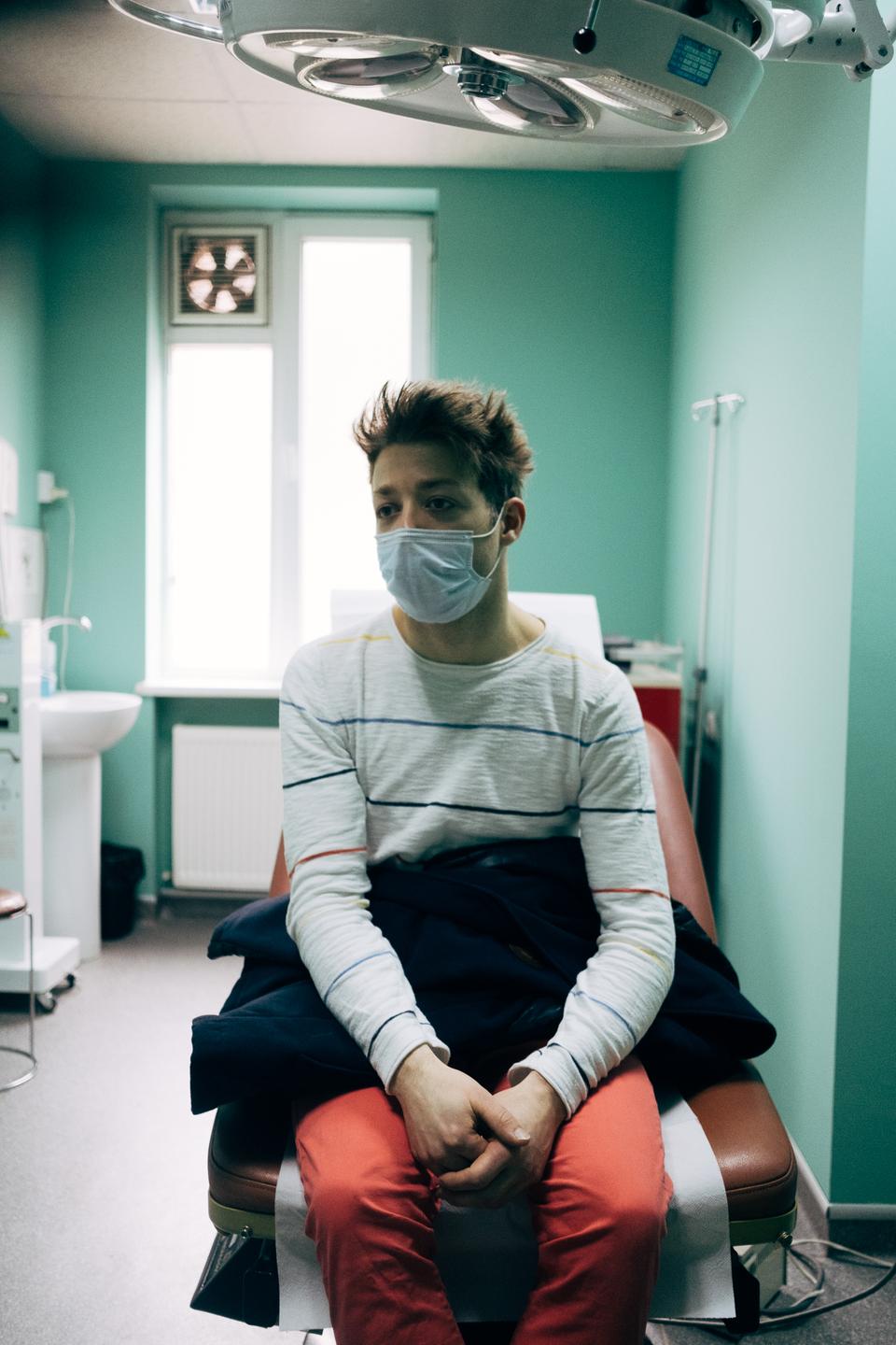 Ein junger Mann sitzt mit Maske auf einem Behandlungsstuhl. Ein junger Mann sitzt mit Maske auf einem Behandlungsstuhl.