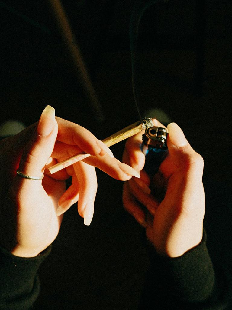 Hände sind aus der Perspektive der Person selbst zu sehen wie sie mit einem Feuerzeug einen Joint anzünden.