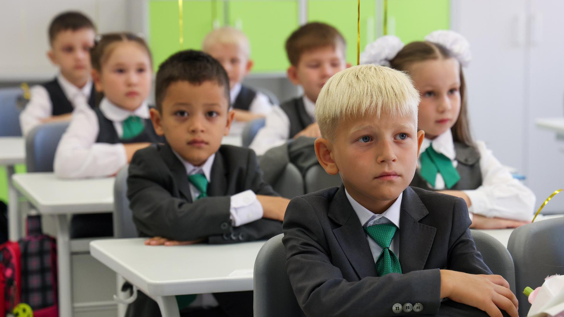 Erstklässler sitzen in der Klasse, in feiner Kleidung und schauen aufmerksam nach vorne. Erstklässler sitzen in der Klasse, in feiner Kleidung und schauen aufmerksam nach vorne.