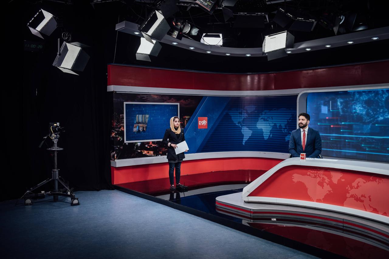 In einem Fernsehstudio steht eine Moderatorin, ein Moderator sitzt an einem Tisch. Sie blicken in unterschiedliche Kameras. In einem Fernsehstudio steht eine Moderatorin, ein Moderator sitzt an einem Tisch. Sie blicken in unterschiedliche Kameras.