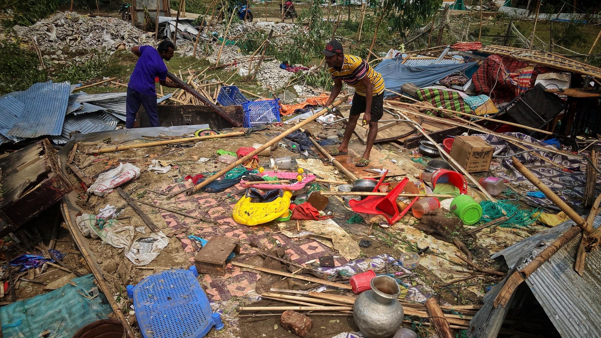Menschen suchen in den Trümmern von beschädigten Häusern nach ihren Sachen. 