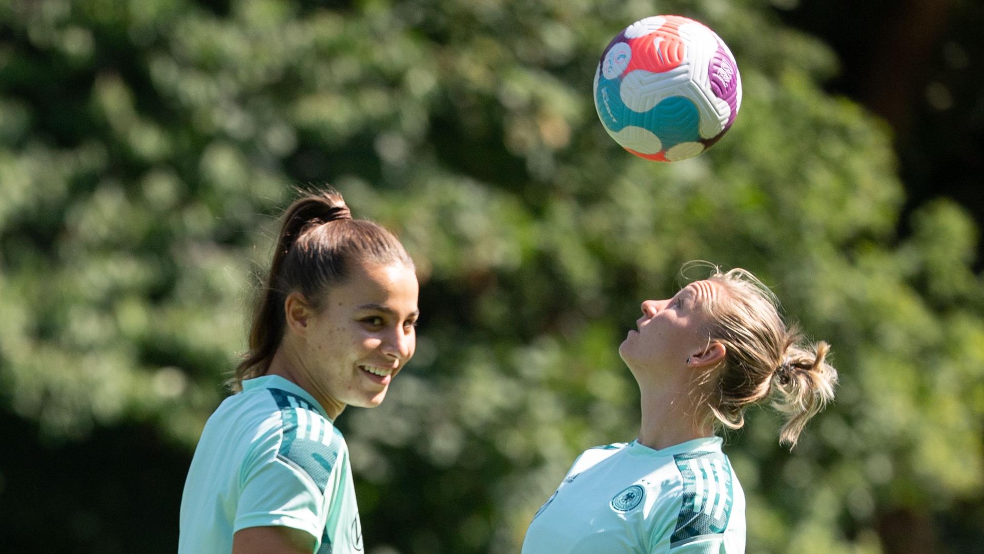 Großbritannien, Watford: Fußball-Nationalmannschaft, Frauen-EM 2022. Deutschlands Alexandra Popp (r) spielt neben Lena Sophie Oberdorf einen Kopfball beim Training.