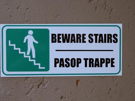 Ein zweisprachiges Warnschild an einem Gebäude in Pretoria macht auf eine Treppe aufmerksam