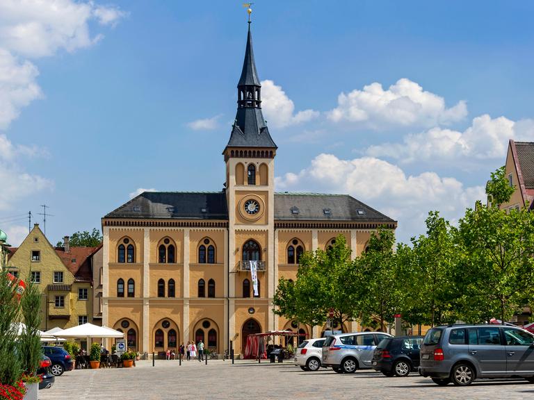 Das Rathaus am Unteren Hauptplatz in Pfaffenhofen an der Ilm in Oberbayern. Im Vordergrund parken Autos.