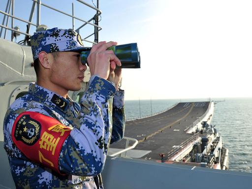 Ein Soldat mit Fernglas an Bord des chinesischen Flugzeugträgers Liaoning.