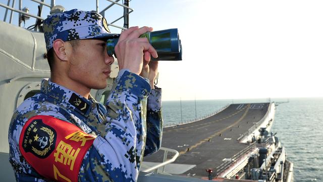 Ein Soldat mit Fernglas an Bord des chinesischen Flugzeugträgers Liaoning.