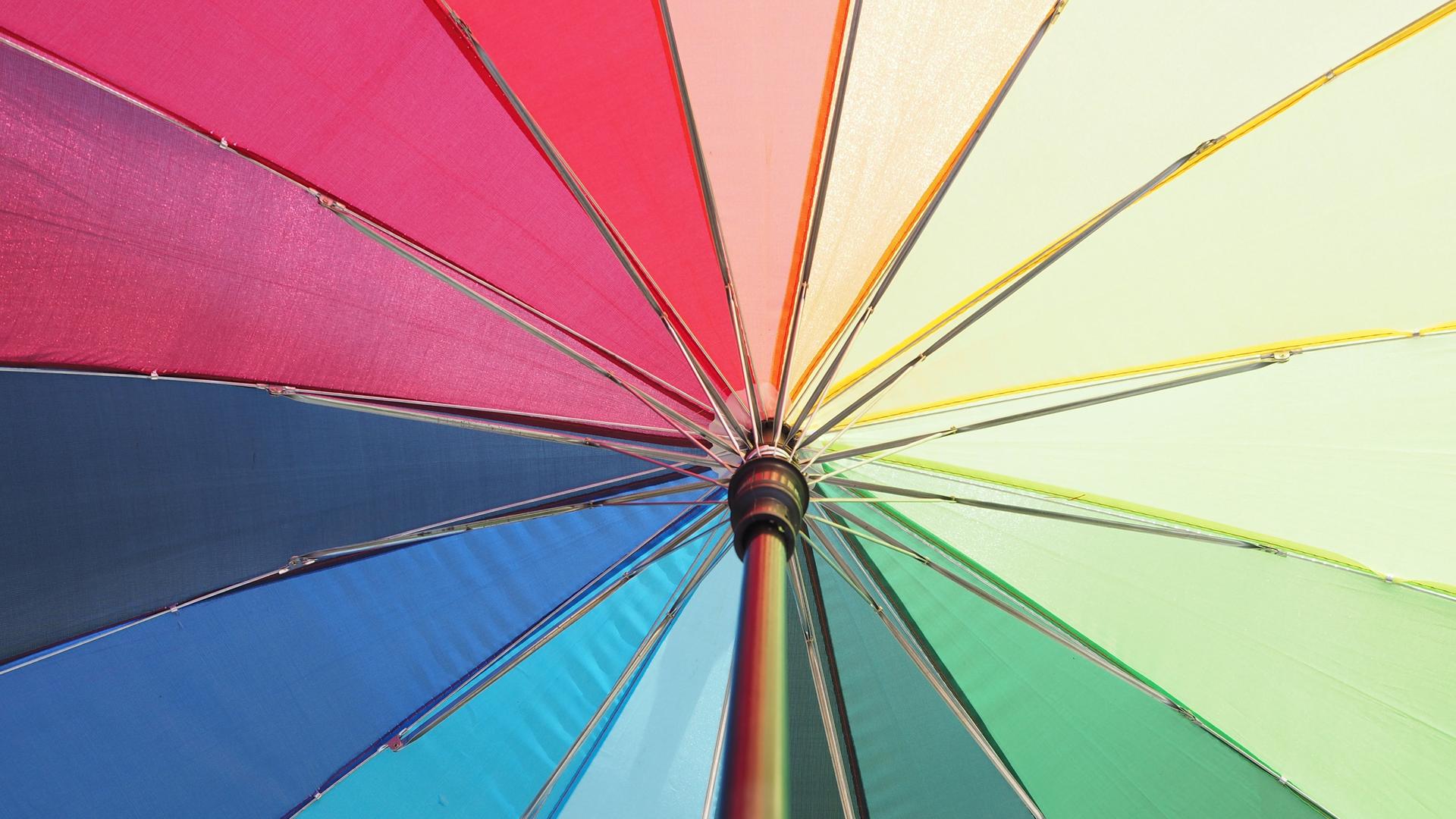 Blick von unten in einen geöffneten, regenbogenfarbenen Schirm