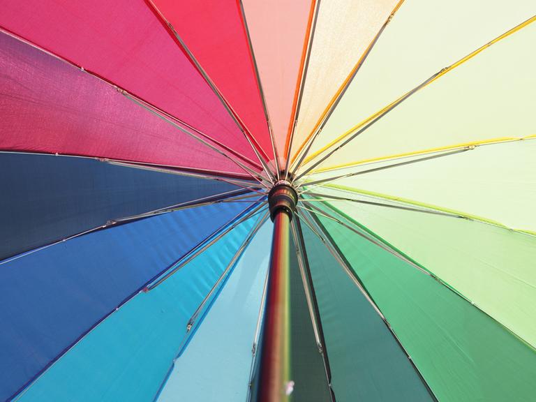Blick von unten in einen geöffneten, regenbogenfarbenen Schirm