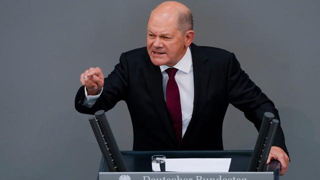 Bundeskanzler Scholz steht im Deutschen Bundestag hinter einem Rednerpult.