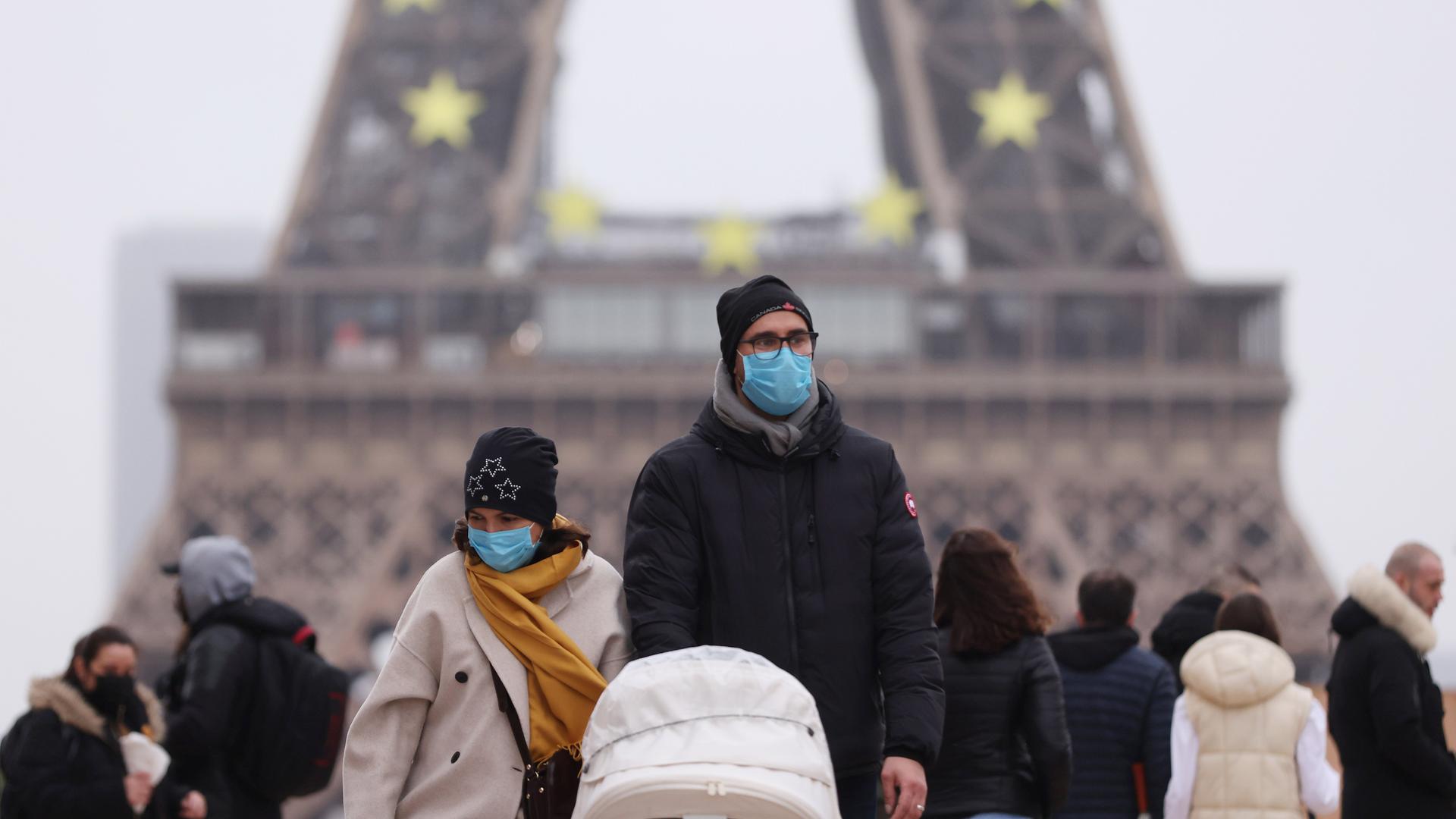 Menschen tragen Schutzmasken und gehen am Trocadero in der Nähe des Eiffelturms in Paris spazieren. Menschen tragen Schutzmasken und gehen am Trocadero in der Nähe des Eiffelturms in Paris spazieren.