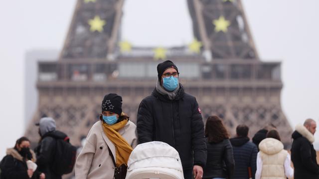 Menschen tragen Schutzmasken und gehen am Trocadero in der Nähe des Eiffelturms in Paris spazieren. 